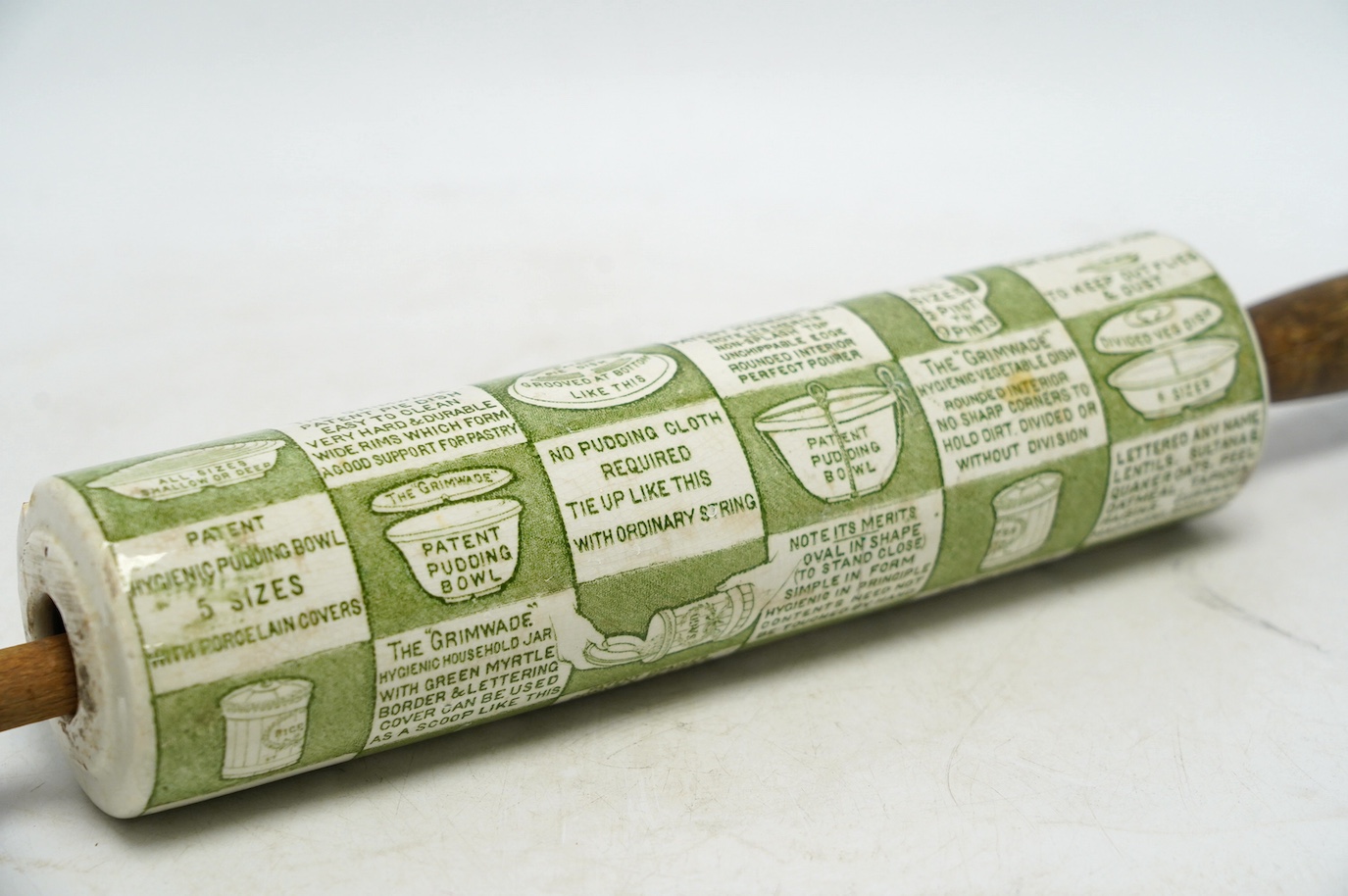 An early 20th century Grimwades green printed earthenware promotional rolling pin, 47cm wide. Condition - poor to fair